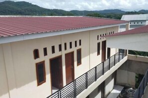 A building with a red roof, multiple windows, and a balcony with a railing. - Homestay Komodo Mountain View (Batu Cermin)