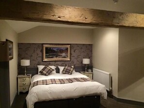 A bedroom with a large bed, two bedside tables, a radiator, and a framed picture on the wall.