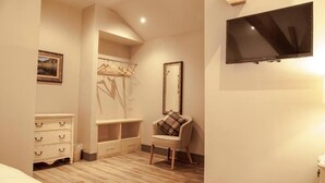 Une chambre à coucher comprenant un lit, une commode, une chaise, un téléviseur et une armoire.