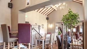 Un espace repas doté d’un plancher en bois, d’un escalier et d’un lustre.