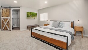 A bedroom with a large bed, a bench, a closet, and a painting on the wall. - Franklin Heart Homestead – Loveland Family Fun (Loveland)