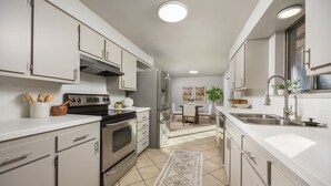 A modern kitchen with white cabinetry, stainless steel appliances, and a central island. - Franklin Heart Homestead – Loveland Family Fun (Loveland)
