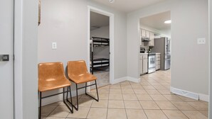 A hallway with two chairs, a kitchen area with appliances, and a bunk bed in the background. - Franklin Heart Homestead – Loveland Family Fun (Loveland)