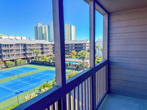 Ein Balkon mit Blick auf einen Tennisplatz und umliegende Gebäude.