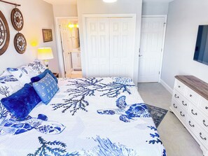 Une chambre à coucher comprenant un lit, une commode, une armoire et un téléviseur.