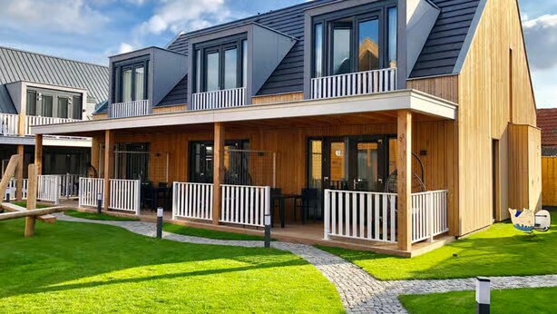 A modern two-story house with a covered patio, large windows, and a sloped roof. - Beautiful Lodge for 5-person Near the Beach (Zoutelande)
