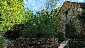 A stone building with a rustic appearance, surrounded by lush greenery and trees. - Dordogne cottage with pool and garden – charm & nature at Le Gouzot (Urval)