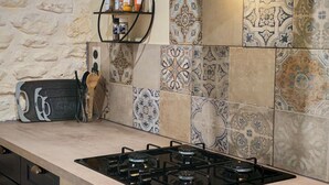 Une cuisine équipée d’une cuisinière à gaz, d’une planche à découper en bois et d’une étagère contenant des ustensiles de cuisine.