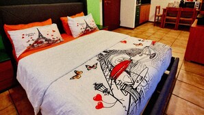 A bedroom with a bed, green walls, a door, a kitchenette, and a dining area. - Bernina Stop & Go apartment - 30 steps to the red train (Tirano)