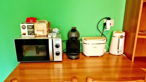 A dining table with a microwave, coffee maker, and a rice cooker. There are two chairs with orange cushions. - Bernina Stop & Go apartment - 30 steps to the red train (Tirano)