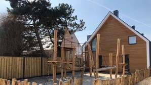 A wooden play structure with a climbing net and a small house-like building. - Beautiful Lodge Parallel to the Shopping Street (Zoutelande)