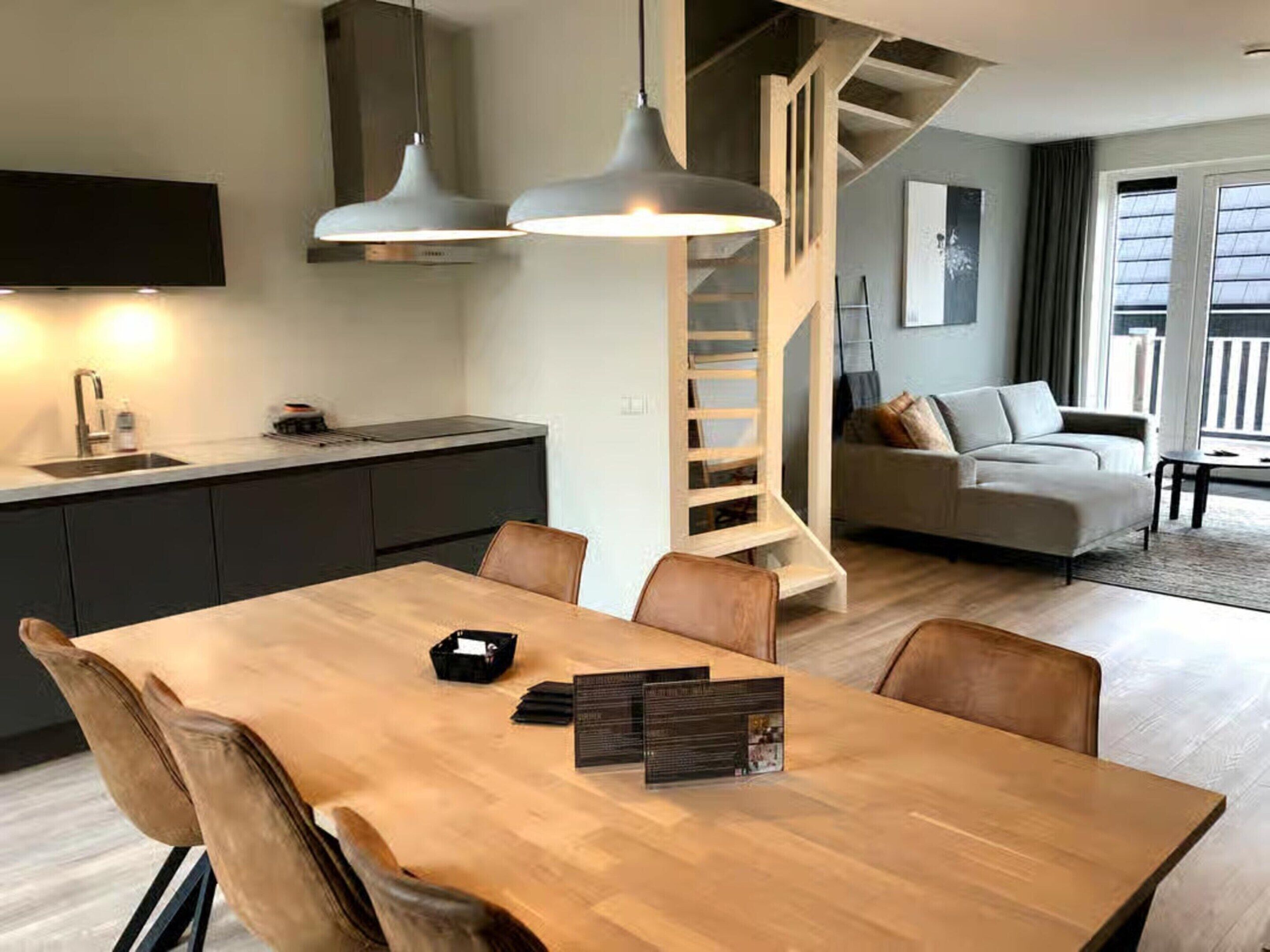 Una cocina moderna con comedor, una escalera y una sala de estar con sofá y mesa de centro.
