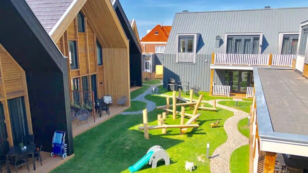 A residential area with modern houses, a playground with a slide, and a paved pathway. - Beautiful Lodge Parallel to the Shopping Street (Zoutelande)