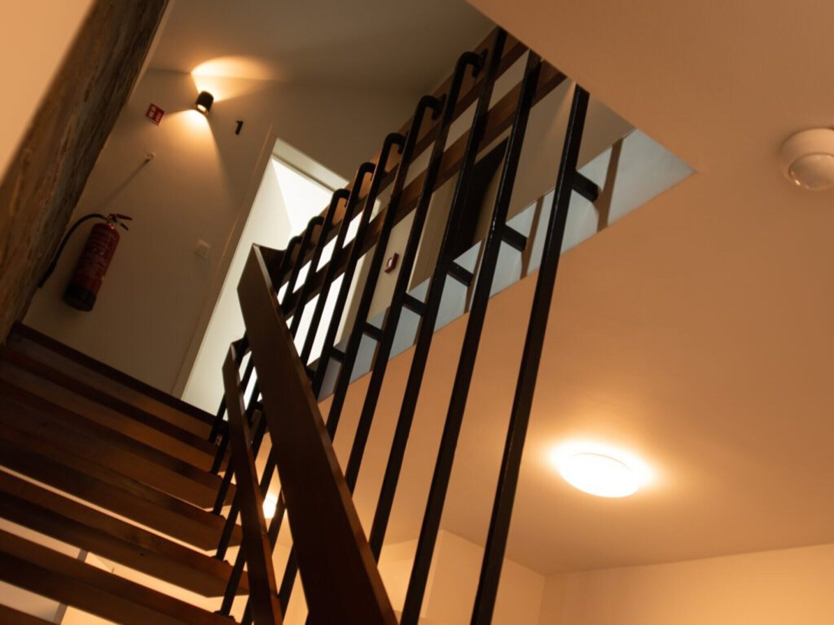 Eine Treppe mit Holzwertlauf und einem an der Wand befestigten Feuerlöscher.