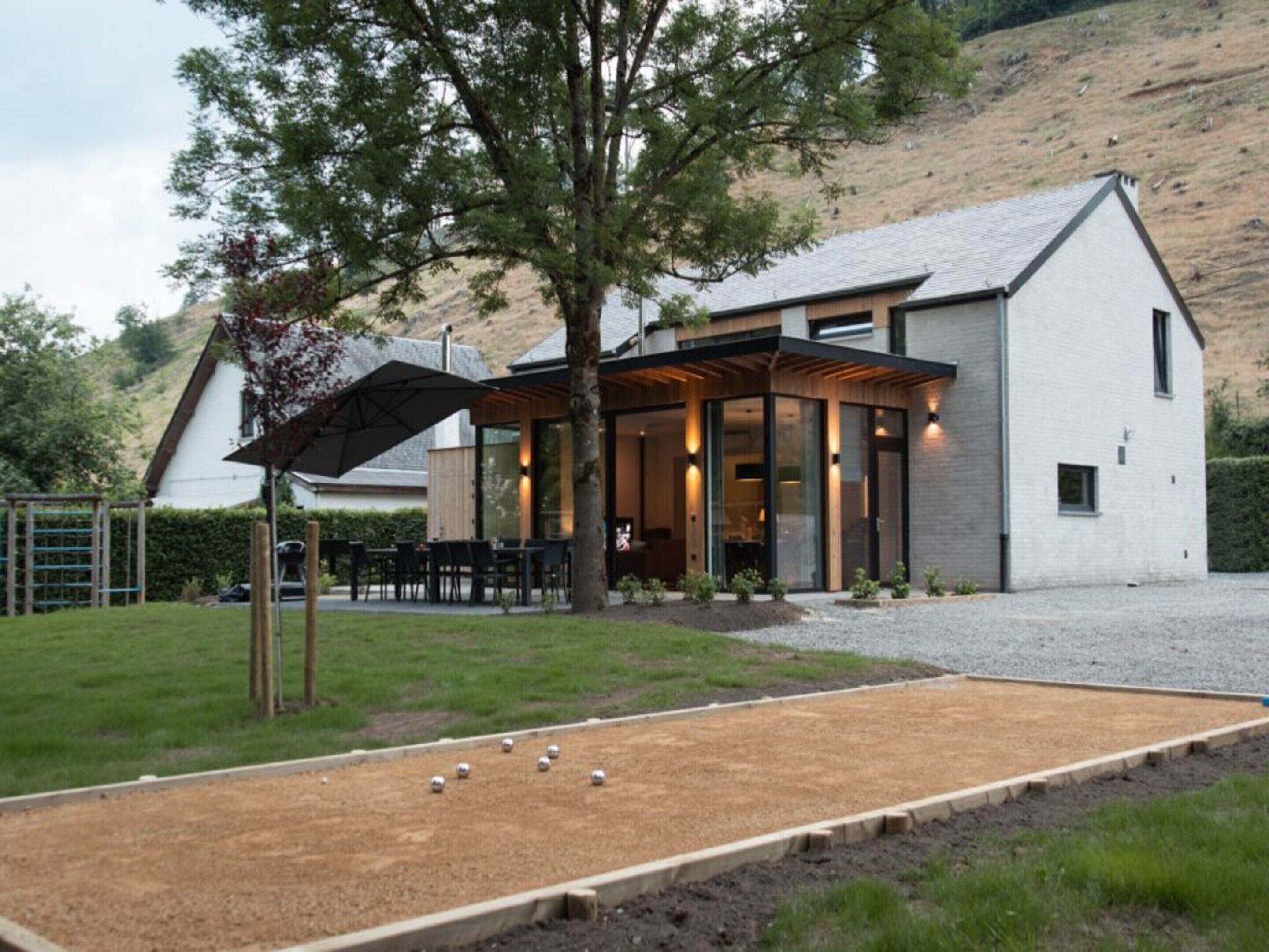 Een modern huis met een overdekte zithoek en een tuin.