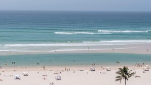 Una playa con agua cristalina, gente y sombrillas.