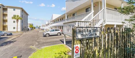 A residential area with a sign for Wolf Bay Villas at 25925 Canal Rd.