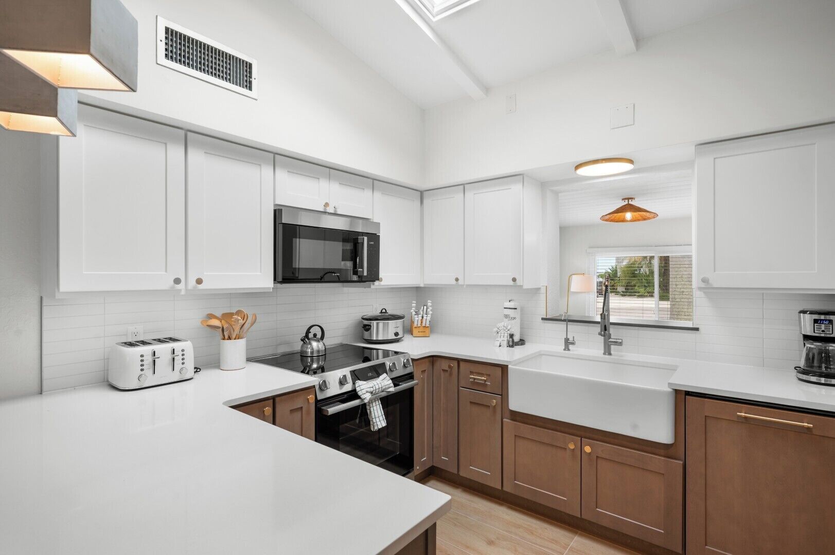 A modern kitchen with white cabinetry, a stainless steel microwave, a gas stove, and a sink.