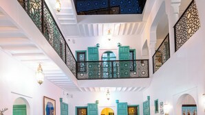 Un intérieur spacieux agrémenté d’un élément aquatique central, de nombreuses portes et d’un plafond haut orné de motifs complexes.