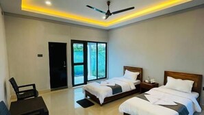 A modern bedroom with two beds, a ceiling fan, and a view of greenery through the windows. - Daosri The Inn (Barangabari)