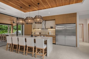 A modern kitchen with a central island, stainless steel appliances, and pendant lighting.