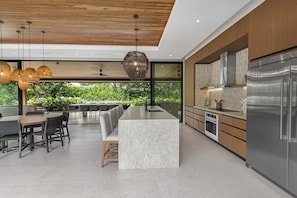 Una cocina moderna con una isla grande, electrodomésticos de acero inoxidable y vistas al exterior.