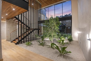 Ein modernes Interieur mit Treppe, Zimmerpflanzen und Blick durch große Fenster.