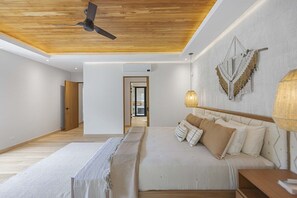 Un dormitorio con una cama, un ventilador de techo, una lámpara de pared y una puerta que da a otra habitación.