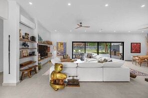 A modern living room with a white sofa, a golden bear sculpture, and a bookshelf. - Casa Campana (Santa Cruz)