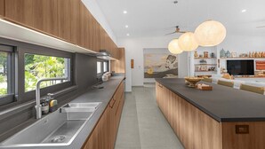 Et moderne køkken med en indbygget ø, rustfrie stålapparater og hængende lamper.