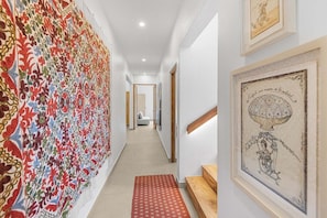 Ein Korridor mit Wandverkleidung, gerahmten Kunstwerken und einer Treppe.