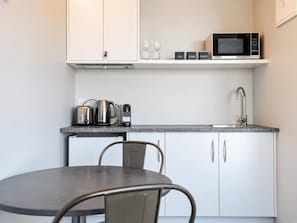 A compact kitchen with white cabinets, a microwave, a coffee maker, and a kettle. - Blue Sky | Lake Views + Private Deck + Stargazing (Lake Tekapo)