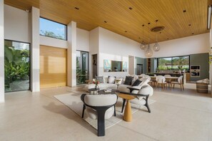 A spacious living area with a modern design, featuring a large sofa set, a coffee table, and a dining area with chairs. - Lingalonga (Guanacaste)