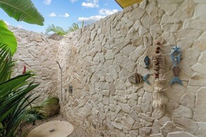 A stone wall with decorative elements and a shower area. - Lingalonga (Guanacaste)