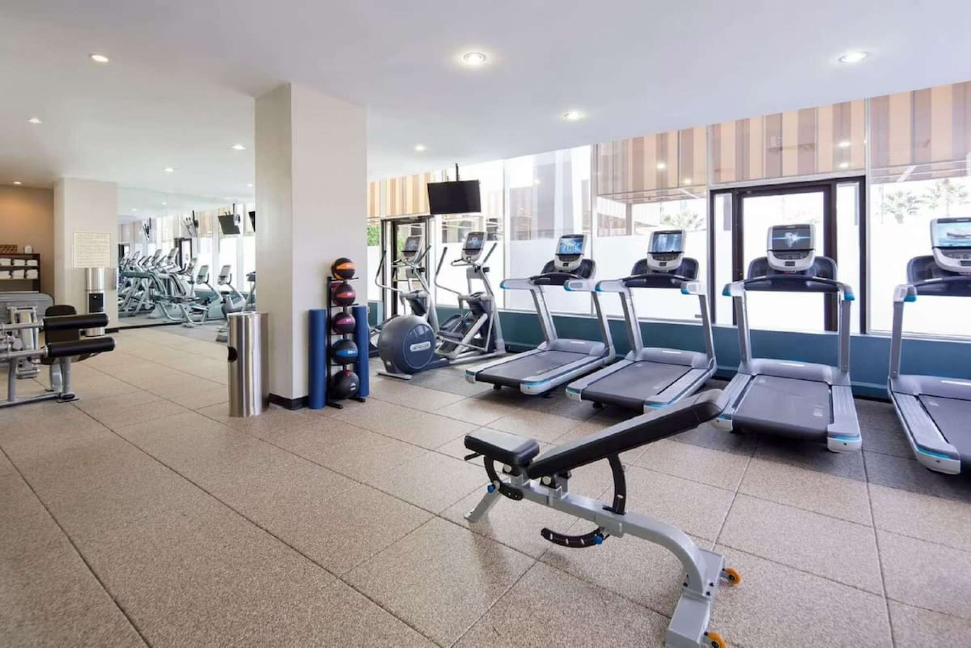 Une salle de sport moderne équipée de tapis de course, d’appareils de musculation et de ballons d’exercice.