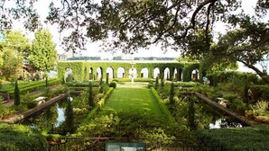 Un jardin à la française avec une pelouse centrale, des allées symétriques et des structures en arc de cercle.
