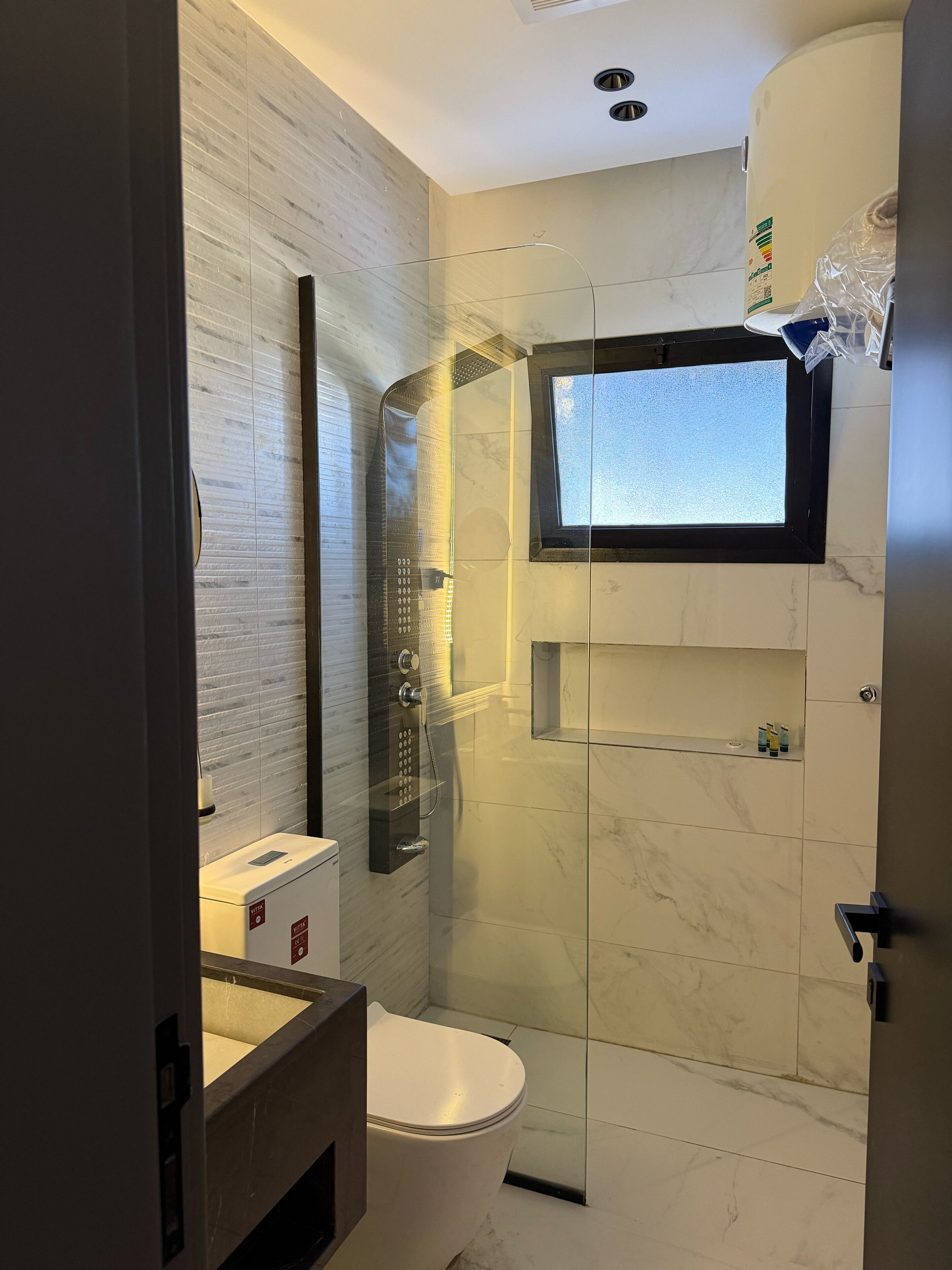 A modern bathroom with a glass-enclosed shower, a toilet, and a vanity.
