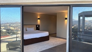 Une chambre à coucher avec un lit, une table de chevet et une vue sur le paysage urbain, visible à travers une porte vitrée.