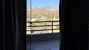 Une pièce dotée d’une grande porte-fenêtre coulissante donnant sur un balcon avec vue sur un paysage montagneux.