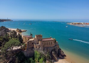 Un château situé sur la côte, avec une plage et une mer d’un bleu limpide.