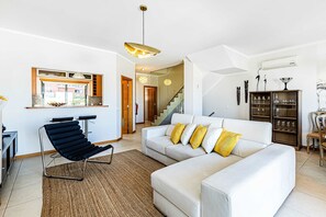 A modern living room with a white sofa, black chair, and a staircase leading to another level.