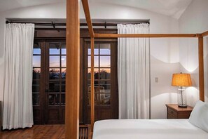 A bedroom with a four-poster bed, a nightstand with a lamp, and a view through a glass door. - Villa Mansita (Tamarindo)