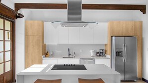 Een moderne keuken met een centraal eiland, roestvrijstalen apparatuur en houten details.