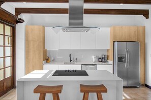 A modern kitchen with a central island, stainless steel appliances, and wooden accents. - Villa Mansita (Tamarindo)