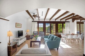 A spacious living room with a television, seating area, and dining space. - Villa Mansita (Tamarindo)