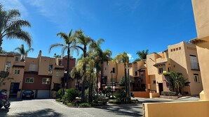 Un quartier résidentiel avec des immeubles à plusieurs étages, des palmiers et une cour dallée.