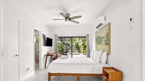 A bedroom with a bed, a ceiling fan, an air conditioning unit, a TV, and a view of the outdoors. - Sleek Kitchenette & Queen Bed (Fort Lauderdale)