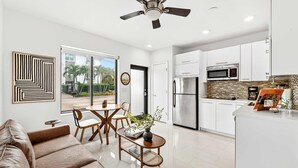 A modern kitchen with white cabinets, stainless steel appliances, and a tiled backsplash. - Sleek Kitchenette & Queen Bed (Fort Lauderdale)