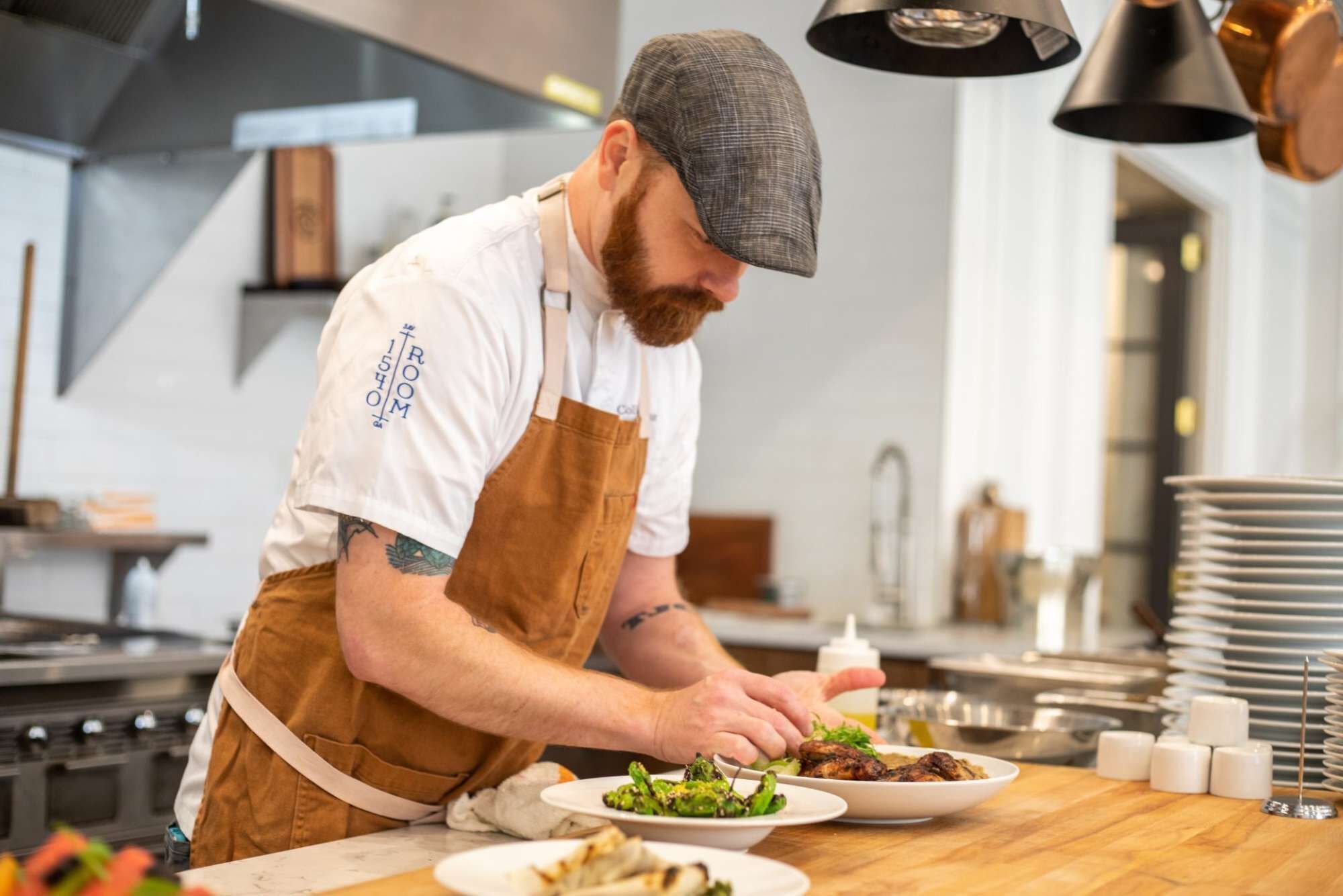 Een kok bereidt eten in een moderne keuken met roestvrijstalen apparatuur en een overzichtelijke, georganiseerde indeling.