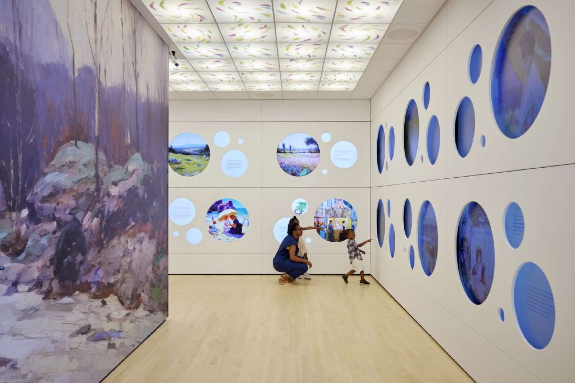 Een kunstgalerie met een groot schilderij aan de linkerkant en ronde afbeeldingen op de muren.